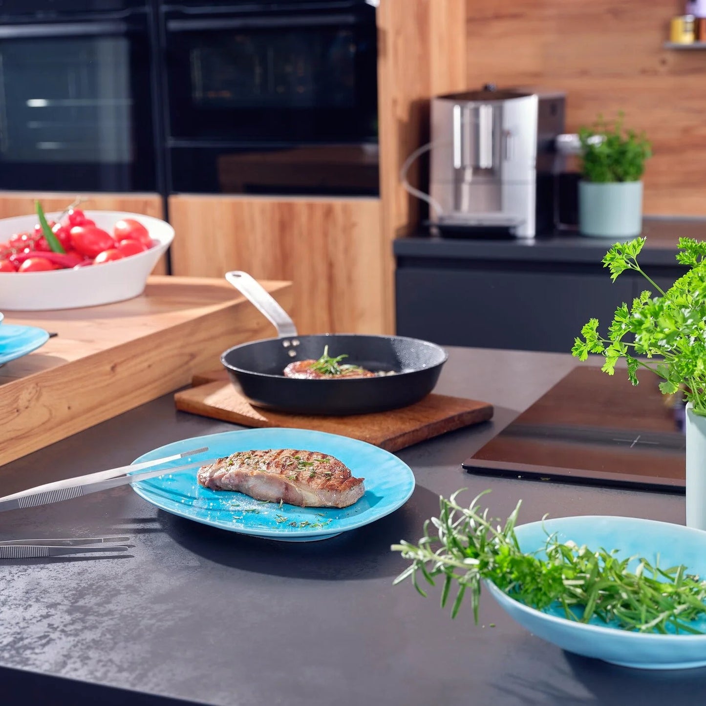 Kitchen counter with plates of food, a pan, and a potted plant.